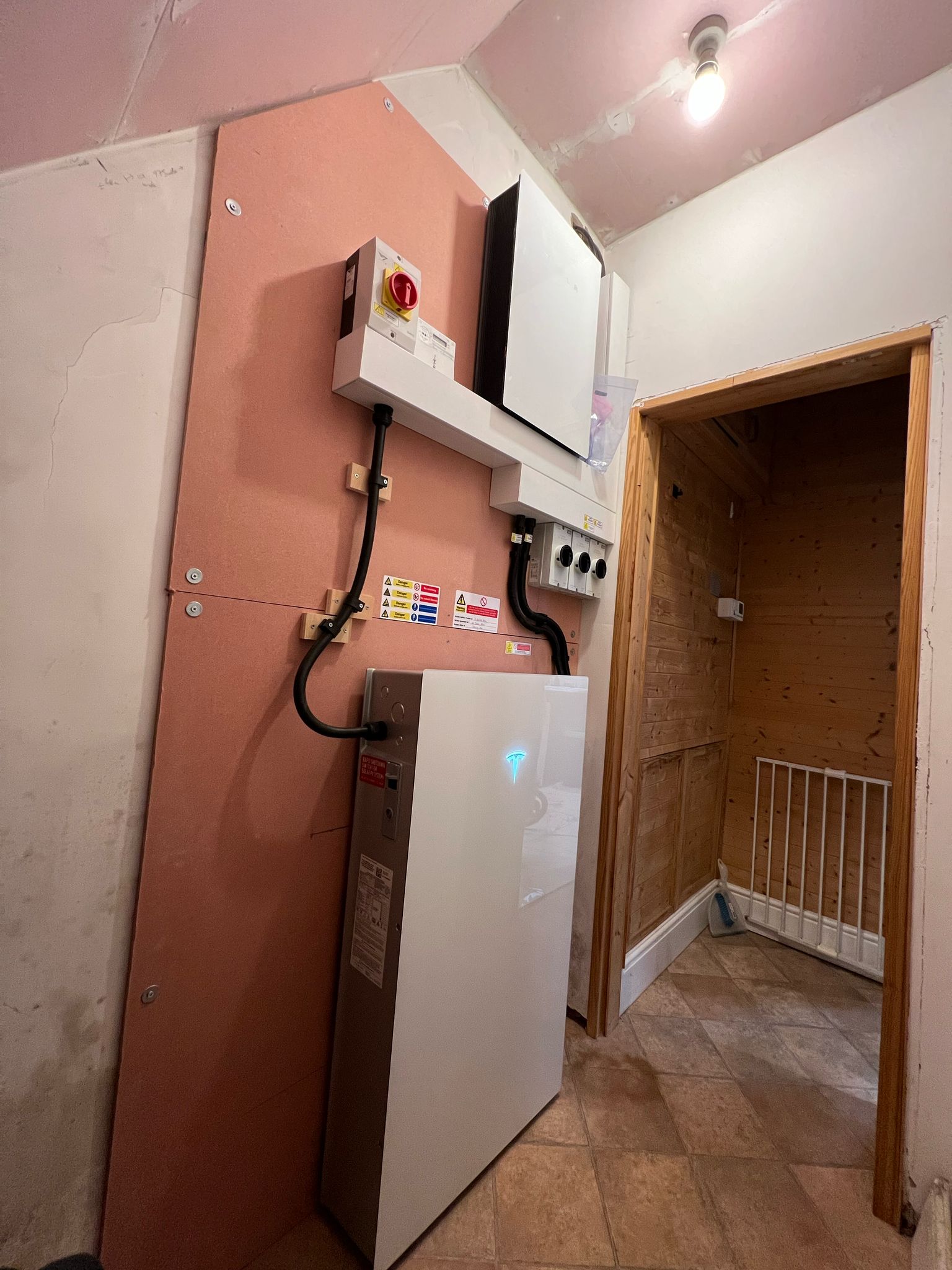 A home battery and inverter installed on a utility room wall with an isolator switch
